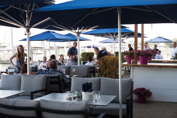 The patio outside at Bronte Boathouse with comfy chairs, tables, and patio umbrellas.